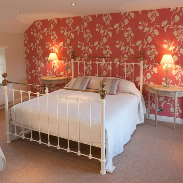 a picture of a cream bed with a decorative red and cream plant feature wall