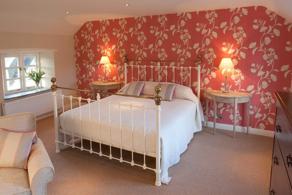 a picture of a cream bed with a decorative red and cream plant feature wall