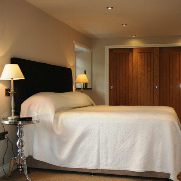 a picture of a cream bedroom with brown wooden doors and a light brown carpet
