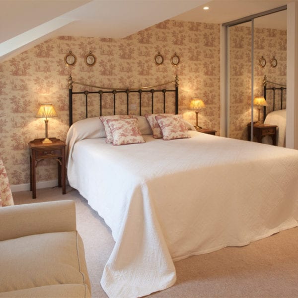 A picture of a stylish cream bedroom with a large cream bed