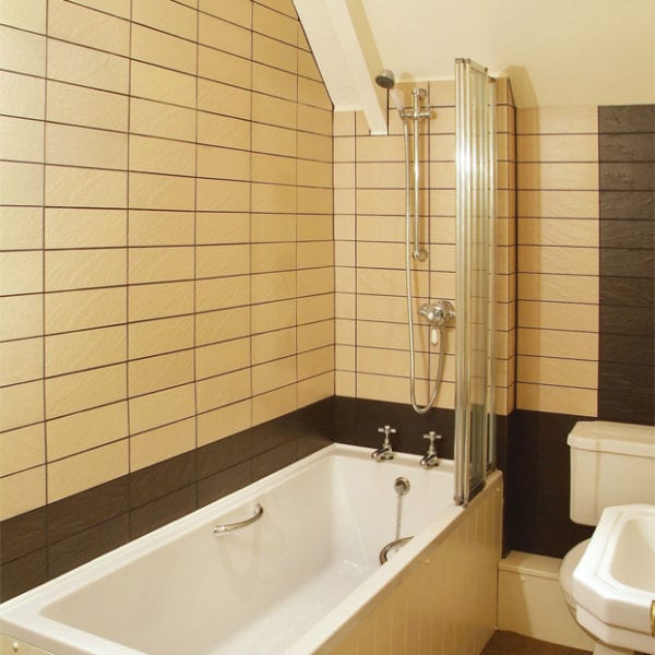 a bathroom with beige tiles and a stand over shower