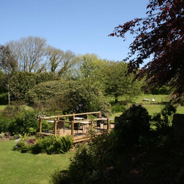 a picture of large garden with a wooden patio centred, with garden furniture