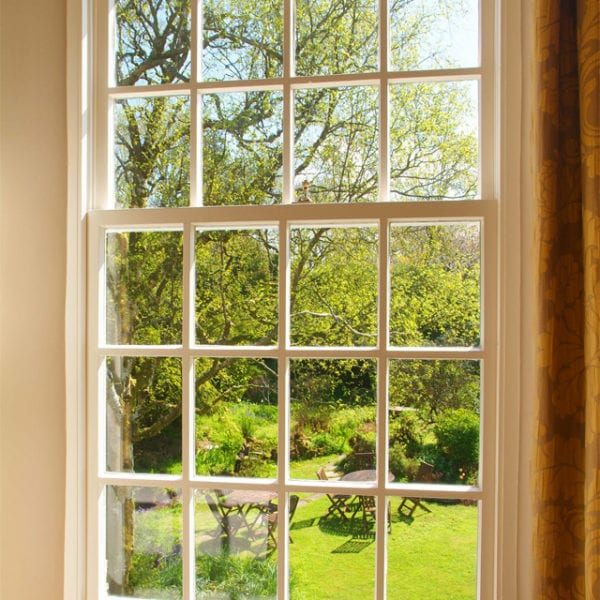 a picture of a window with a view of the garden, trees and garden furniture outside