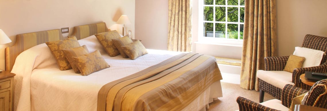 a picture of a cream bedroom with gold accessories such as cushions, curtains and headboards