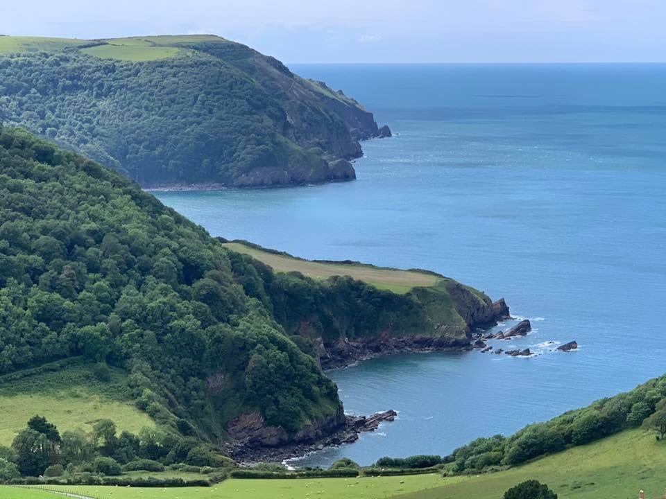 a picture of green hills with the blue sea surrounding it