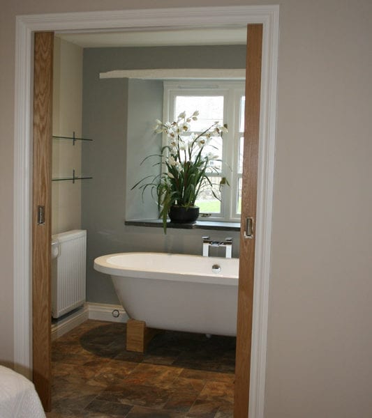 a picture of a bathroom with a white freestanding bath with a vase of lilies