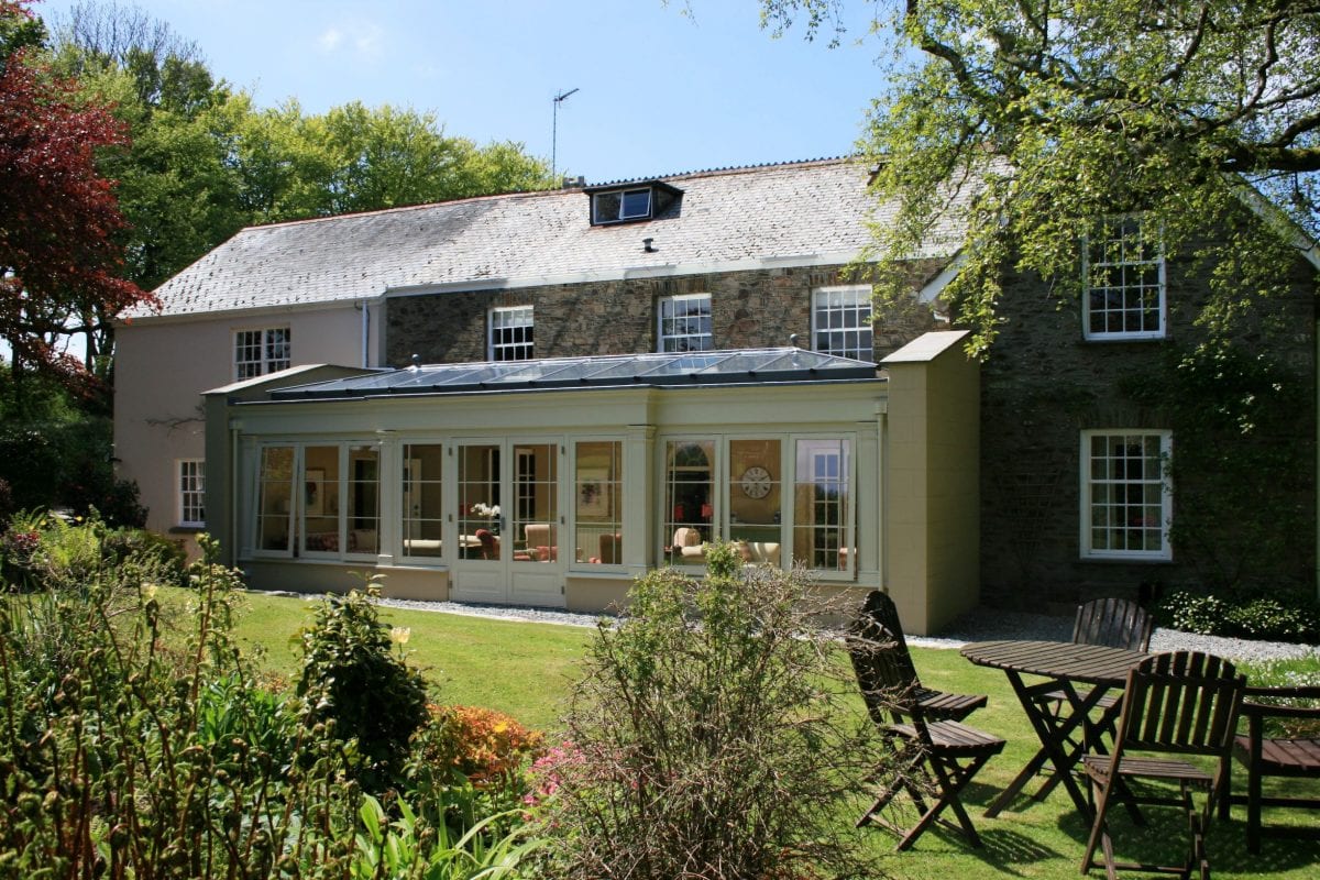 a picture of a cream and brick house with garden furniture outside on the grass