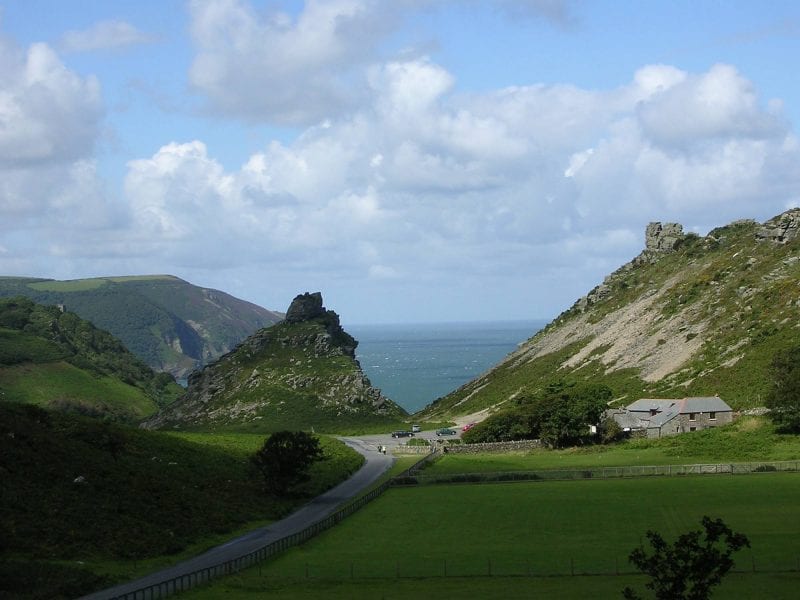 a picture of large rocky hills covered in grass with a pathway leading down on the blue sea